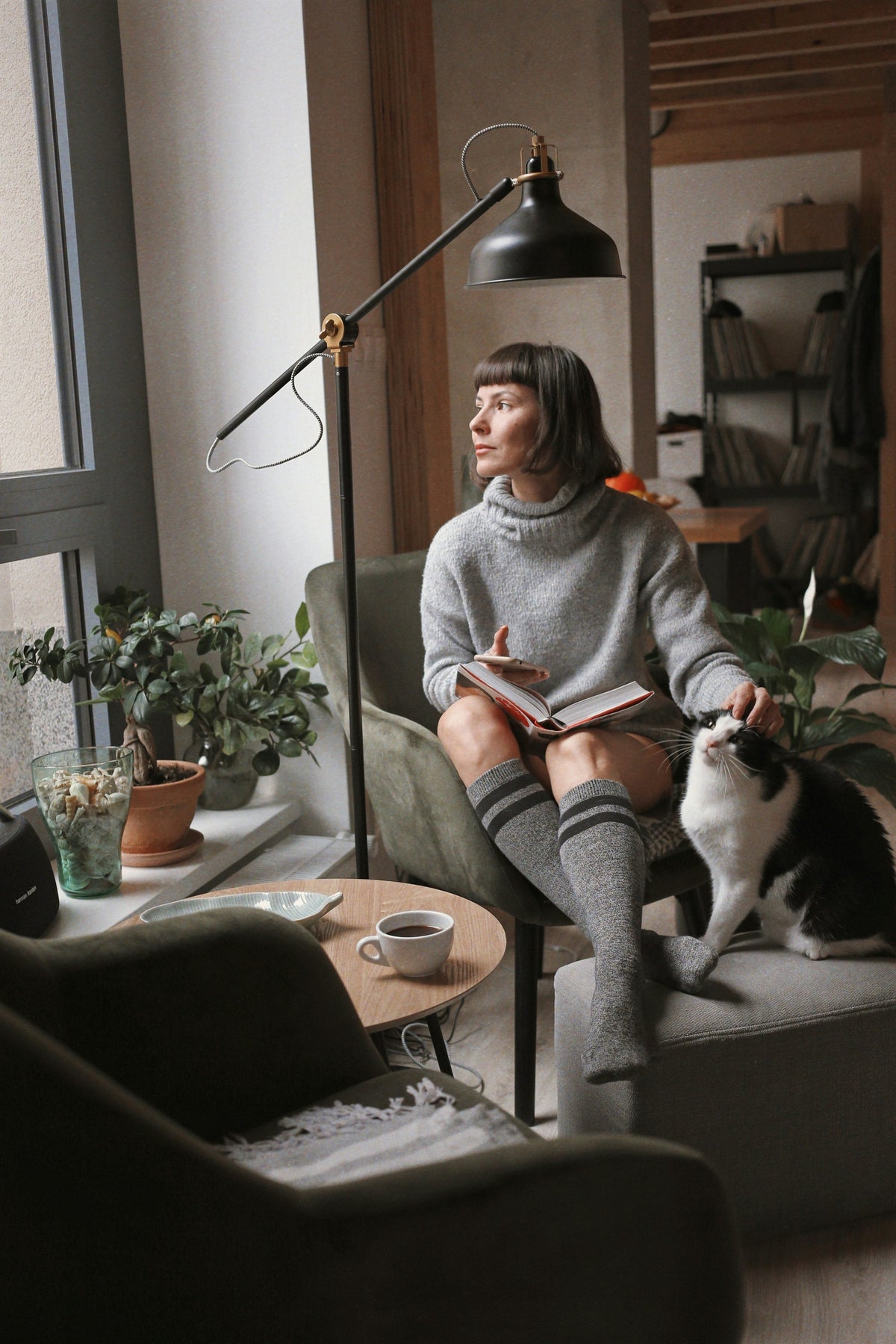 Woman reading in a reading chair beside her black and white cat
