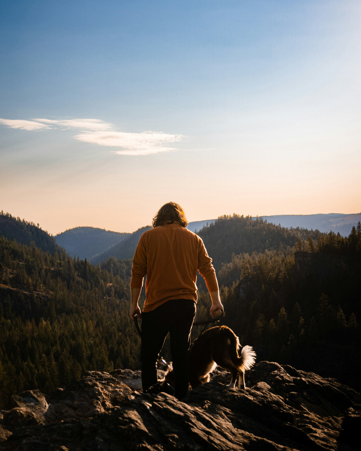 Hiker and dog watching a mountain sunset